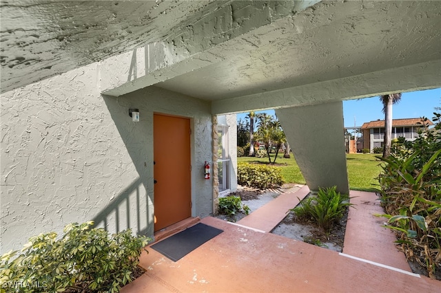 entrance to property featuring stucco siding and a yard