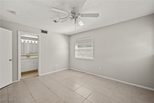 unfurnished bedroom with visible vents, a textured ceiling, light tile patterned floors, baseboards, and ceiling fan