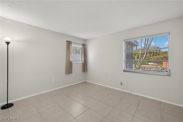 spare room featuring a textured ceiling and baseboards