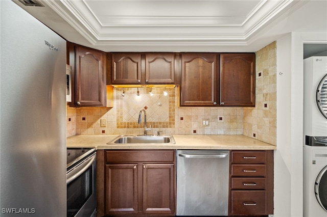 kitchen with stacked washer / dryer, ornamental molding, stainless steel appliances, and a sink