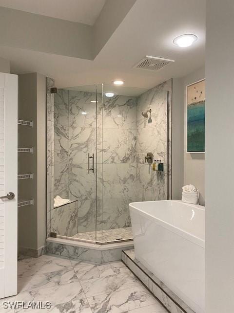 bathroom with a marble finish shower, visible vents, a freestanding tub, marble finish floor, and a sink