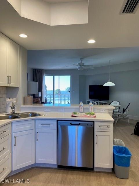 kitchen with visible vents, a sink, white cabinets, light countertops, and dishwasher