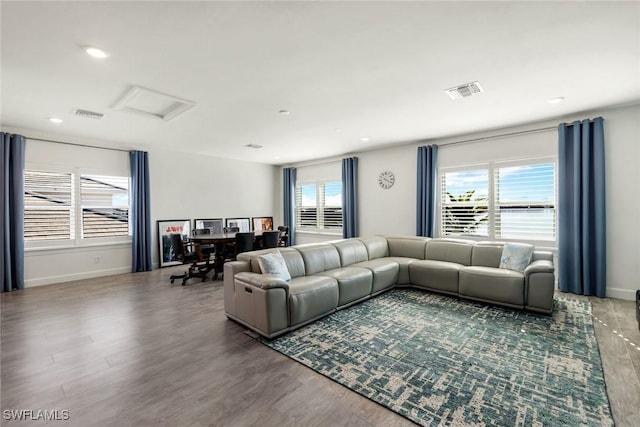 living room with visible vents, baseboards, attic access, and wood finished floors