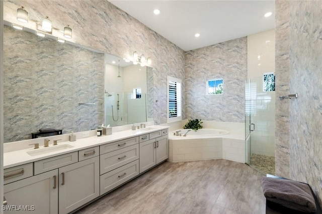 bathroom featuring a shower stall, a garden tub, double vanity, and a sink