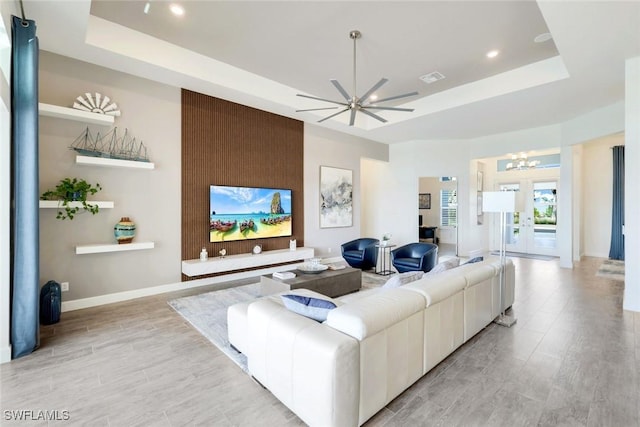 living room featuring visible vents, a raised ceiling, a chandelier, and light wood finished floors