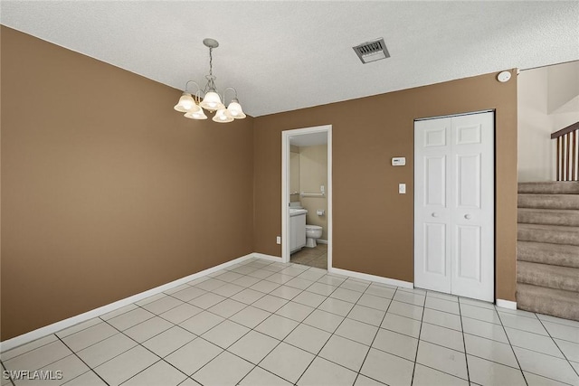 empty room with light tile patterned floors, visible vents, baseboards, and stairs