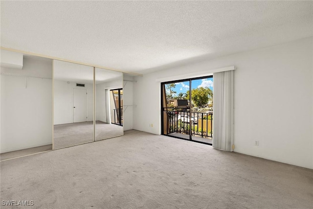 unfurnished bedroom featuring access to exterior, carpet floors, and a textured ceiling