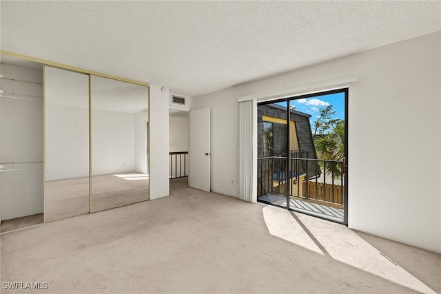 unfurnished bedroom with access to exterior, visible vents, a textured ceiling, and carpet