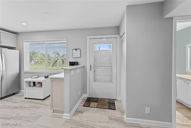 foyer entrance with baseboards, plenty of natural light, and marble finish floor