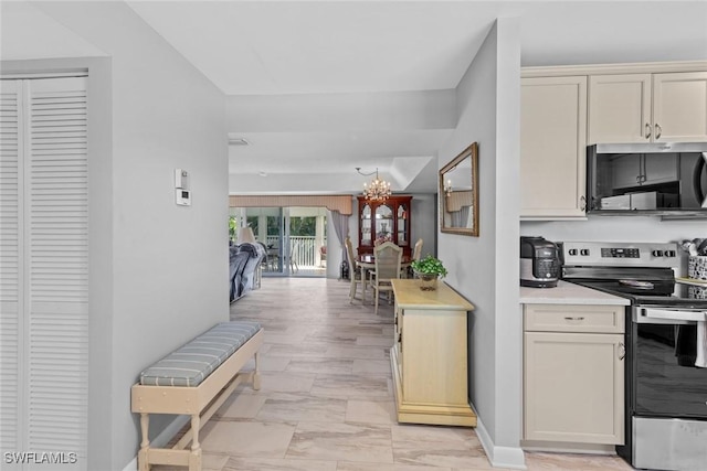 kitchen with baseboards, open floor plan, light countertops, an inviting chandelier, and stainless steel appliances