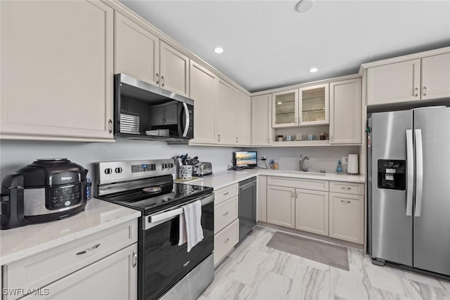 kitchen featuring marble finish floor, a sink, light stone counters, recessed lighting, and appliances with stainless steel finishes