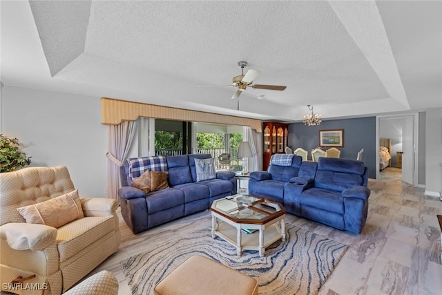 living room featuring a tray ceiling, ceiling fan with notable chandelier, and a textured ceiling