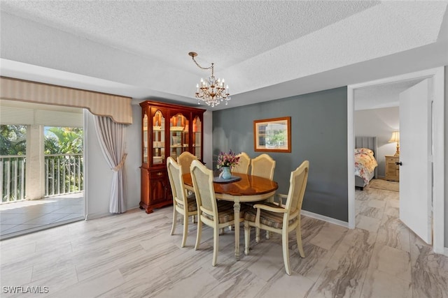 dining room with an inviting chandelier, baseboards, a tray ceiling, and a textured ceiling