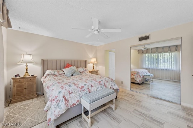 bedroom with a ceiling fan, baseboards, visible vents, and a textured ceiling