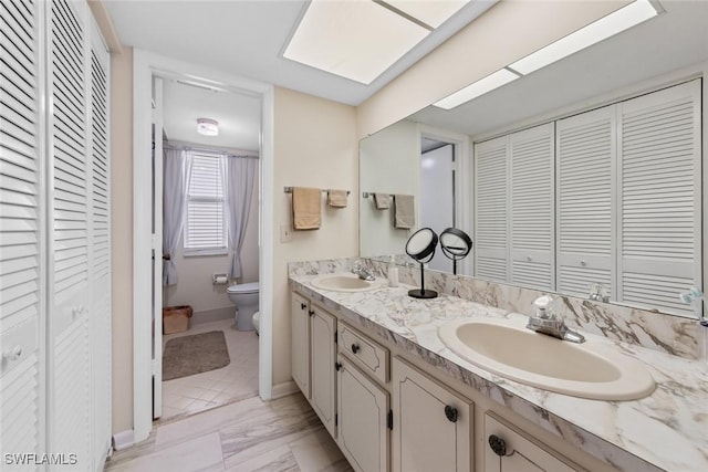 full bathroom with a sink, a closet, toilet, and double vanity