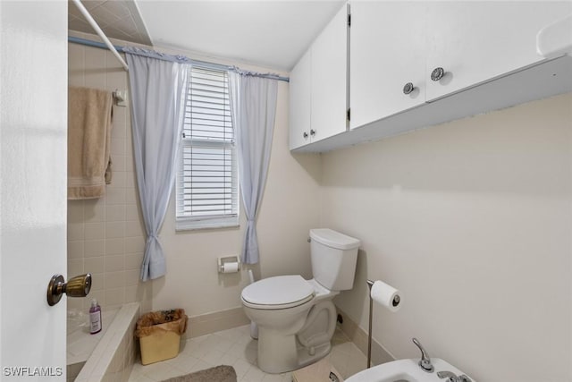 bathroom with baseboards, tiled shower, toilet, and a bidet