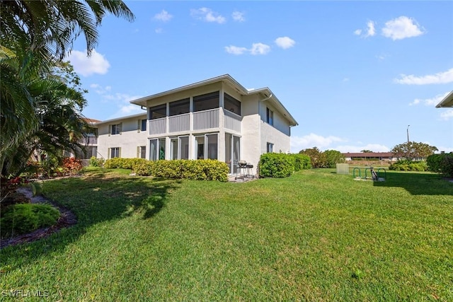 back of property with stucco siding, a yard, and a sunroom