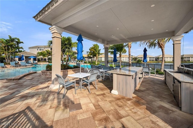 view of patio featuring exterior kitchen, a community pool, and a sink