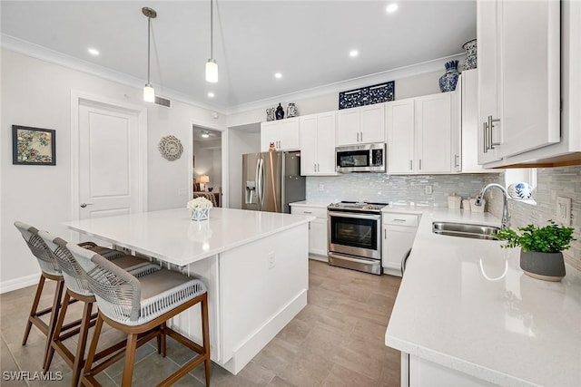 kitchen with ornamental molding, a center island, appliances with stainless steel finishes, and a sink