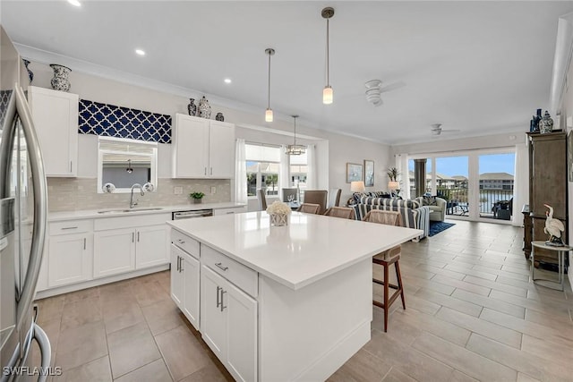 kitchen with tasteful backsplash, open floor plan, light countertops, stainless steel refrigerator, and a sink