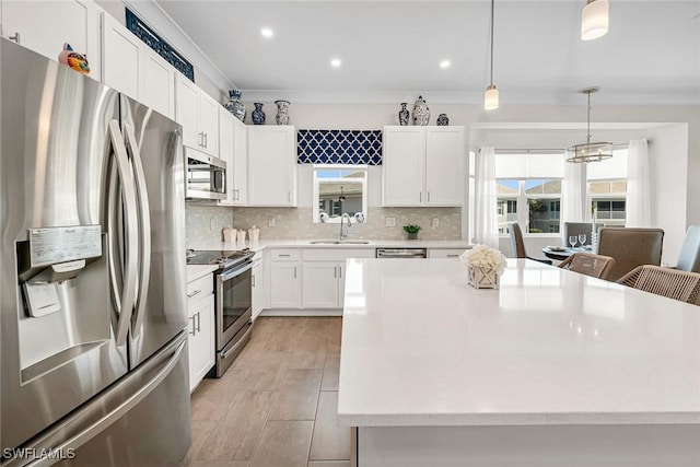 kitchen with a sink, backsplash, white cabinetry, appliances with stainless steel finishes, and light countertops