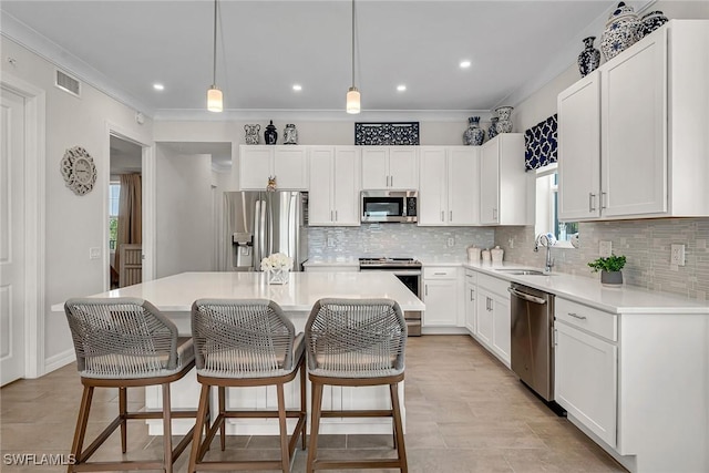 kitchen featuring visible vents, a sink, appliances with stainless steel finishes, crown molding, and a center island