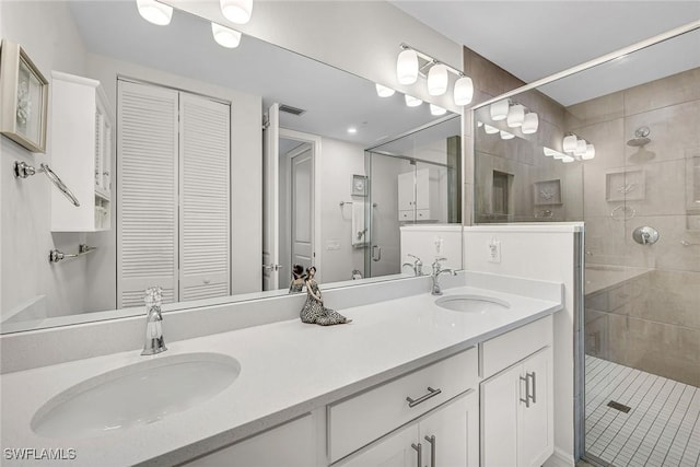 bathroom featuring a sink, a closet, double vanity, and a shower stall