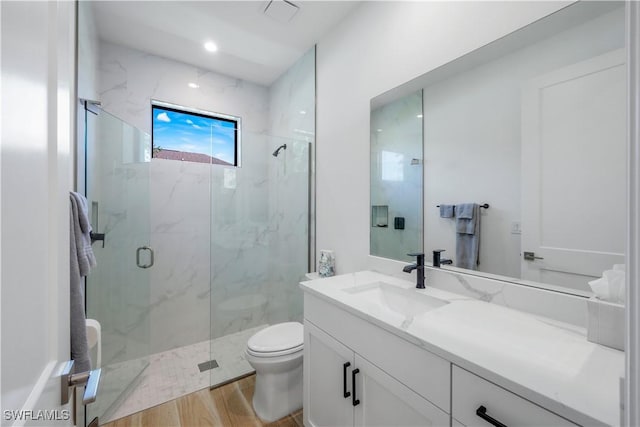 full bathroom with a marble finish shower, toilet, vanity, and wood finished floors