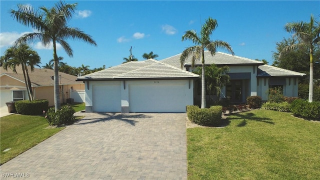 ranch-style home featuring a front yard, decorative driveway, a garage, and stucco siding