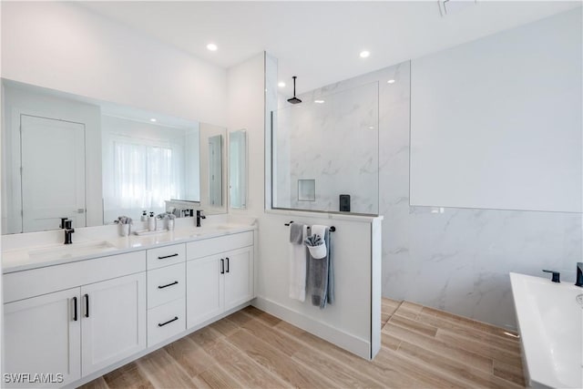 full bathroom featuring a sink, a marble finish shower, and wood finished floors