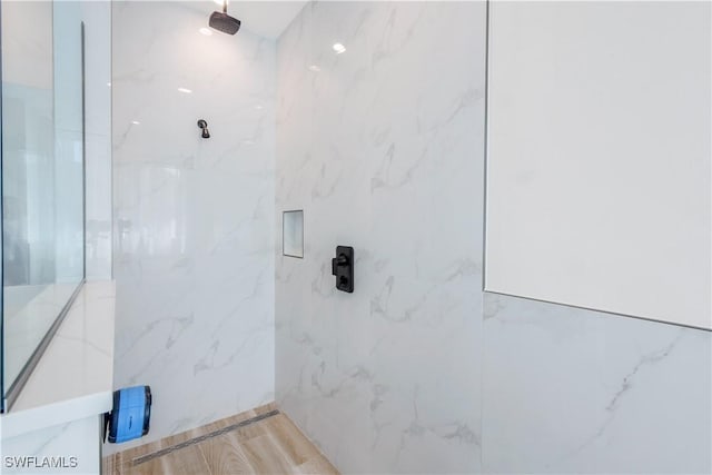 bathroom with wood finished floors and a marble finish shower