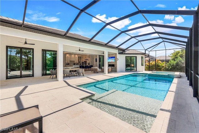 view of pool featuring a pool with connected hot tub, ceiling fan, outdoor lounge area, a lanai, and a patio area