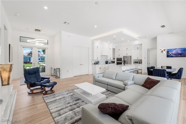 living room with visible vents, recessed lighting, french doors, and light wood-type flooring
