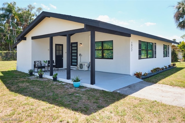 view of front facade with ac unit, stucco siding, and a front yard