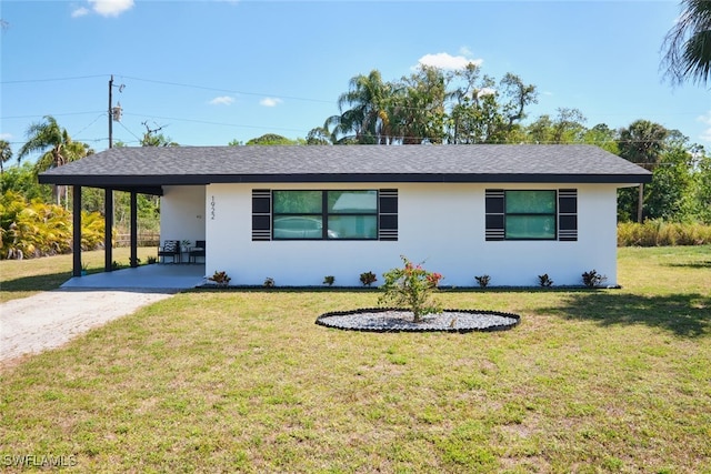 ranch-style house with an attached carport, a front yard, a shingled roof, stucco siding, and dirt driveway