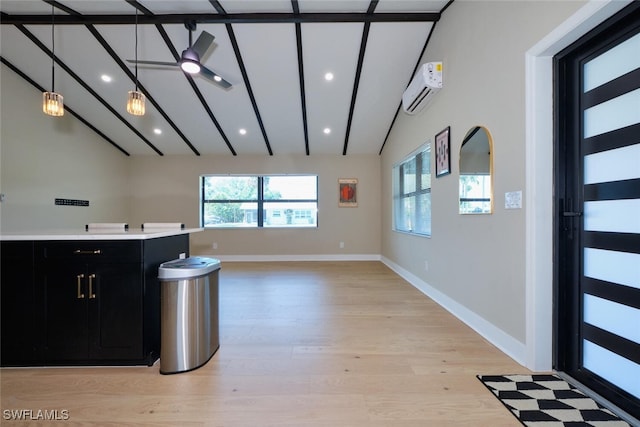 kitchen with light wood finished floors, vaulted ceiling with beams, light countertops, a wall unit AC, and dark cabinetry