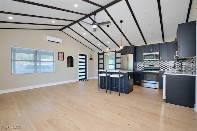 kitchen with a wall mounted air conditioner, a center island, stainless steel appliances, a barn door, and a breakfast bar area