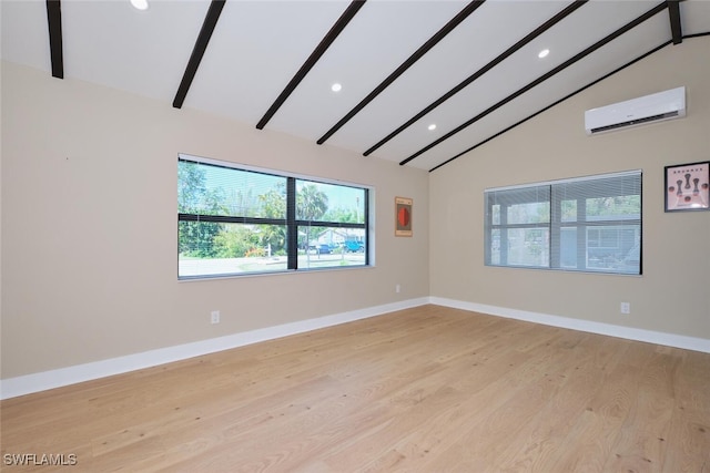 spare room featuring beam ceiling, a healthy amount of sunlight, light wood-style flooring, and a wall mounted AC