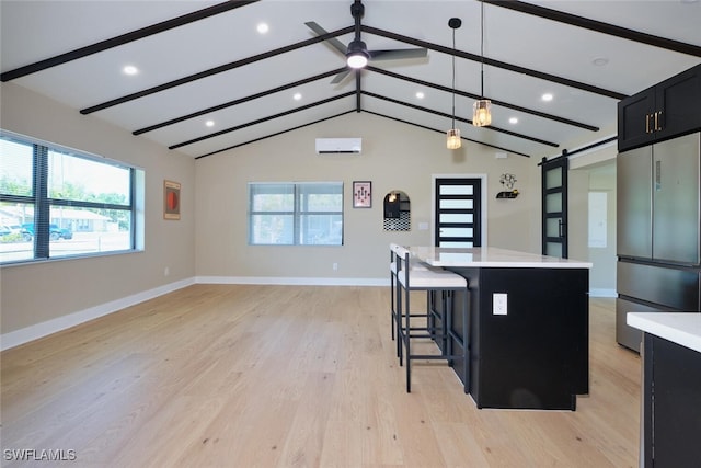 kitchen with stainless steel refrigerator, lofted ceiling with beams, dark cabinetry, a barn door, and light countertops