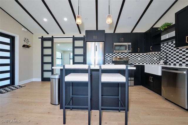 kitchen featuring tasteful backsplash, a breakfast bar area, stainless steel appliances, and a barn door