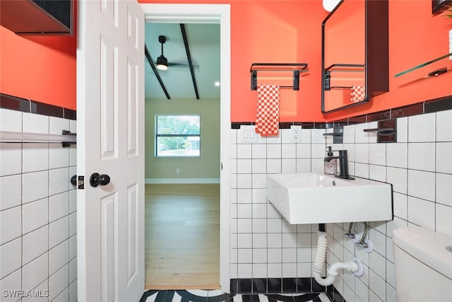 bathroom featuring wood finished floors, a sink, ceiling fan, tile walls, and toilet