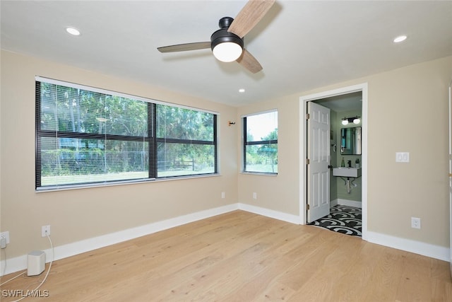 unfurnished bedroom featuring wood finished floors, baseboards, recessed lighting, ceiling fan, and ensuite bathroom