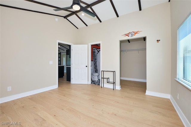 unfurnished bedroom with a spacious closet, light wood finished floors, baseboards, a closet, and high vaulted ceiling