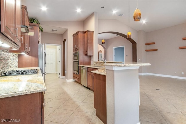 kitchen with a peninsula, light tile patterned flooring, arched walkways, stainless steel appliances, and brown cabinets