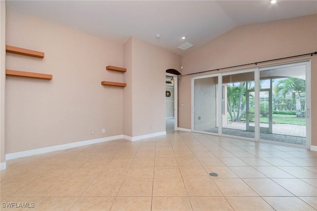 unfurnished room featuring vaulted ceiling, light tile patterned floors, baseboards, and arched walkways