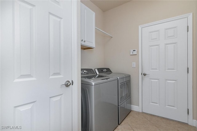 clothes washing area featuring light tile patterned floors, baseboards, cabinet space, and washing machine and dryer