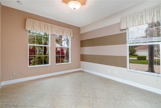 tiled empty room featuring baseboards