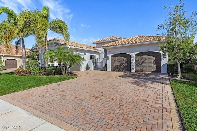 mediterranean / spanish house with a tiled roof, decorative driveway, and a garage