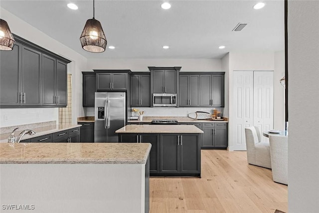 kitchen featuring visible vents, pendant lighting, light stone counters, stainless steel appliances, and light wood-style floors