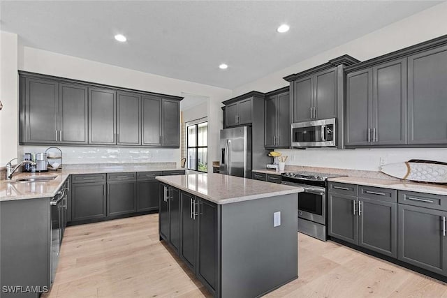 kitchen featuring a sink, light stone counters, a center island, and stainless steel appliances